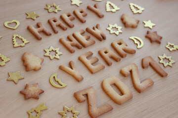 Fototapeta na wymiar Happy New year cookies. Baked cookie letters on wooden table with shiny decorations