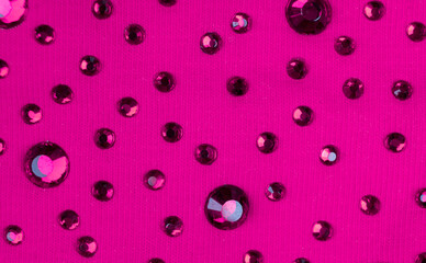 Macro shot pink knitted fabric with many rhinestones pattern. Fashion cloth background texture