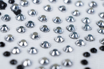 Macro shot white knitted fabric with many rhinestones pattern. Fashion cloth background texture