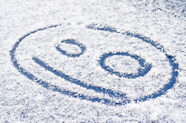 Fototapeta na wymiar Smiling emoji face drawn on the snow
