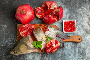top view sliced fresh fish with pomegranates on light-dark background fruit ocean raw seafood