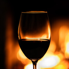 A glass of red wine on the background of the fireplace lights