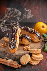 front view delicious choco eclairs with cookies on dark floor dessert cake sweet