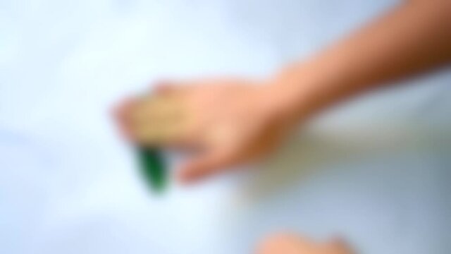 Blurred background. Green paint smeared hands through white paper.