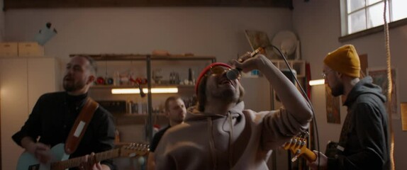 MED Friends playing music during their rock band rehearsal repetition inside a garage. Vocals, guitars and drums. Shot with 2x anamorphic lens