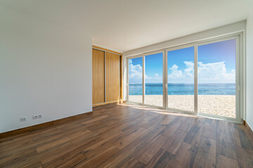 Empty room with dark wooden floating laminate flooring. House interior, wide bedroom or living room space. Newly beach apartment or house with sea, view. Wood floor. Real state or property management