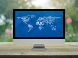 Start up business flat icon with global words world map on desktop modern computer monitor screen on wooden table over blur pink flower and tree, Happy new year 2021 global business start up concept, 