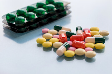 Packagings with pills, colorful pills and capsules on a blue background. Drugs addiction concept.