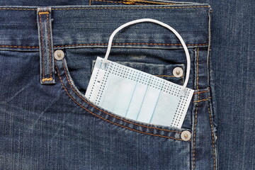 Protective face mask is lying in side pocket of jeans. Concept for new lifestyle after coronavirus...