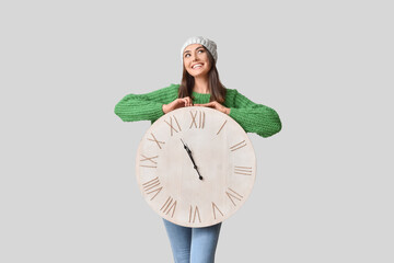 Beautiful young woman with clock on grey background