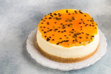 Passion fruit cheesecake on a white plate on a gray concrete background. Delicious homemade cake. Selective focus, copy space