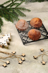 Freshly baked muffins with powdered sugar.  Spruce branches and wooden decorations complete the composition.  Light background.  Vertical frame.