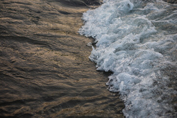 Beautiful contrasting landscape: white foam wave on the dark, smooth surface of the river water