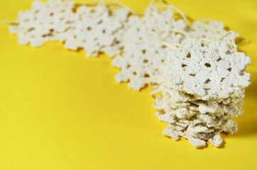 A stack of crochet white snowflakes on a yellow background with a copy space. High quality photo