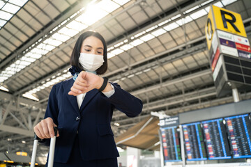Air hostess wearing face mask, checking time for flight in the airport