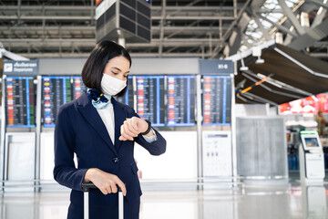 Air hostess wearing face mask, checking time for flight in the airport