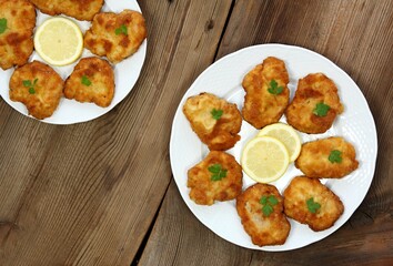 Pork schnitzels served on the plate. Decorated with sliced lemon and parsley. Brown rustic table. Top view, flat lay.
