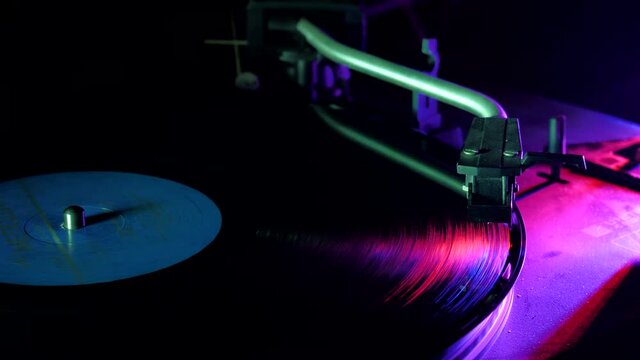 hands placing the vintage turntable on a spinning vinyl record. the vinyl record is spinning. the needle plays on a vintage vinyl record