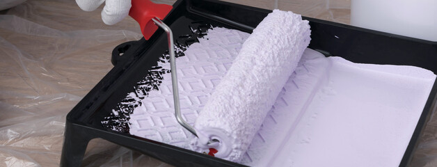 close-up, impregnation of the roller with light paint, at the beginning of work on painting the...