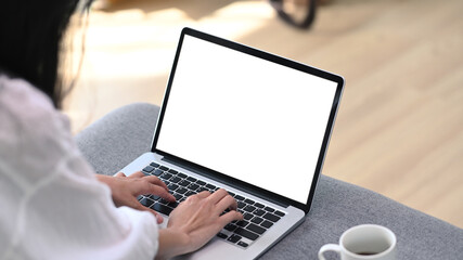 Close up view of young female freelancer working with computer laptop while sitting on couch in...