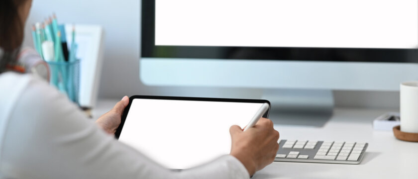 Young female graphic designer relaxing at her workspace and using computer tablet.
