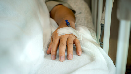 Cannula on the male patient's hand on the bed in the ward