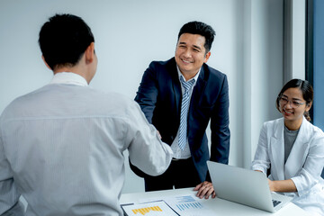 Fototapeta premium Shaking hands after businesswoman and businessmen team meeting to plan strategies to increase business income. Have a brainstorming graph analysis and discussing for the new target success