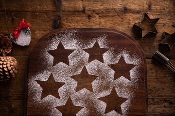preparation of Christmas cookies. Star-shaped imprint left with icing sugar for cookie decoration on wooden cutting board.