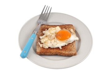 Oeuf au plat sur une tranche de pain de mie dans une assiette avec une fourchette en gros plan sur fond blanc