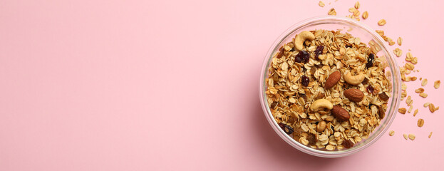 Bowl with tasty granola on pink background