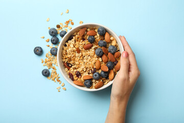 Female hand hold bowl with granola on blue background