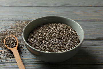 Bowl and spoon with chia on wooden background