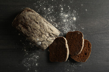 Fresh baked rye bread and flour on black background