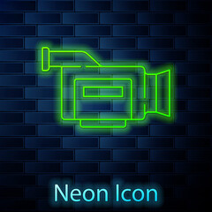 Glowing neon line Cinema camera icon isolated on brick wall background. Video camera. Movie sign. Film projector. Vector.