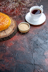 front view sweet baked bun with cup of tea on a dark background dough bread cake pie