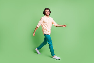 Full length body size profile side view of attractiv cheery guy wearing casual clothes going isolated over bright green color background