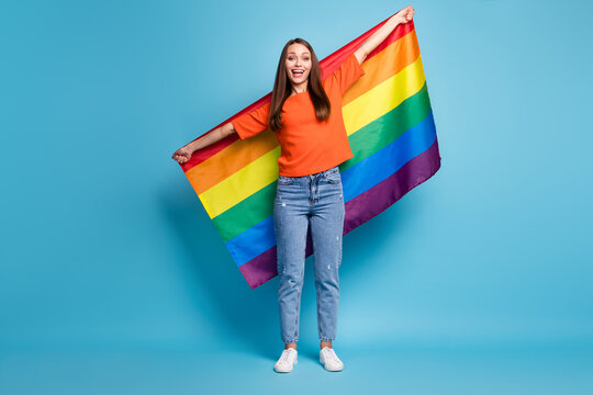 Full length photo of shiny lgbt lady dressed red t-shirt holding hands arms rainbow flag isolated blue color background