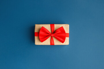 Gift in craft box with red bow on classic blue background. Surprise your loved one. The concept of the day of St. Valentine's, weddings, birthday, New Year, Christmas, dad or mom day