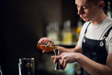 An experienced bartender prepares an alcoholic cocktail. No face, close-up, copy space