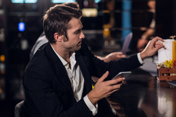 beautiful young guy surfing the Internet in a smartphone behind the bar in a nightclub.