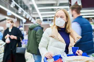 woman in mask buying food in shop at coronavirus epidemic