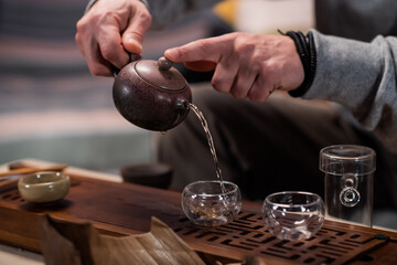 A man treats a guest to authentic ripe vietnamese tea on a special gongfu board made of bamboo. Traditions of eastern tea drinking