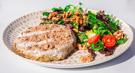 Fresh baked traditional Moroccan Pastilla with dates, salad and walnuts close up