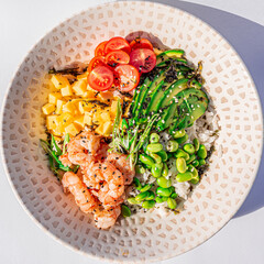 Hawaiian shrimps poke bowl with rice, edamame, mango, cherry tomatoes, avocado, sesame seeds and seaweeds. Buddha bowl. Diet food