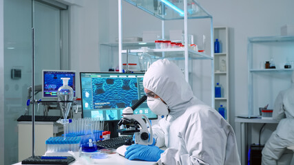 Fototapeta na wymiar Scientist in ppe suit working in laboratory using modern microscope with slides. Team of chemists researcher examining virus evolution using high tech for vaccine scientific research against covid19