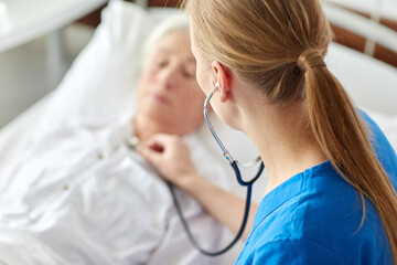 medicine, healthcare and old age concept - female doctor or nurse with stethoscope checking...