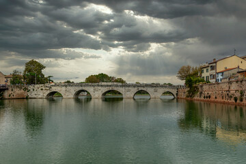Fototapeta na wymiar The ancient Tiberius Bridge in Rimini, Italy, under a dramatic sky
