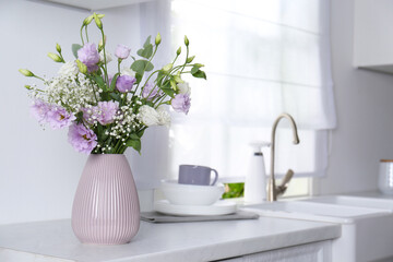 Fototapeta na wymiar Beautiful bouquet with Eustoma flowers on countertop in kitchen. Space for text
