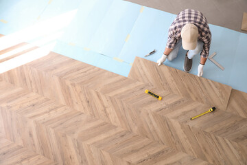 Worker installing laminated wooden floor indoors, above view - Powered by Adobe