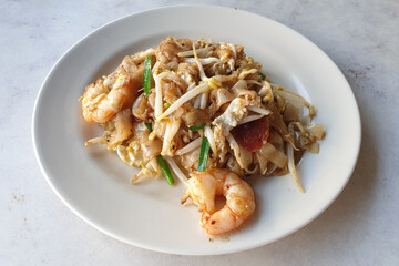 Traditional charcoal stir fried flat noodles with prawns, bean sprouts, chives and chili paste, Penang famous Char Koay Teow.